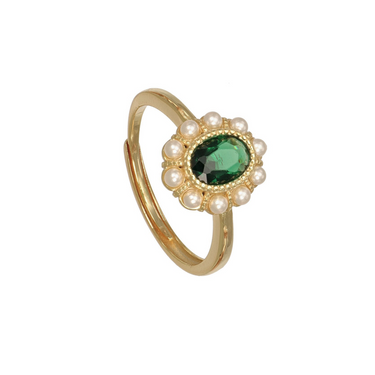 A gold-plated ring with a central oval green gemstone surrounded by a halo of small white faux pearls,