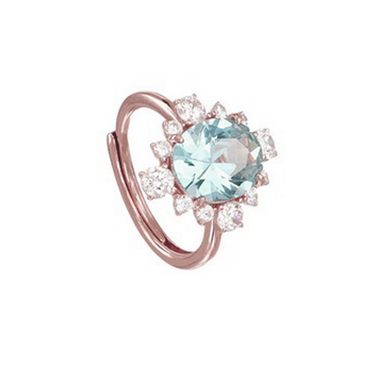 A rose gold ring featuring a large light blue round-cut center stone surrounded by a halo of small clear accent stones