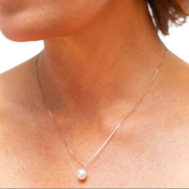 Close-up of a woman wearing pearl earrings and a necklace with a white background