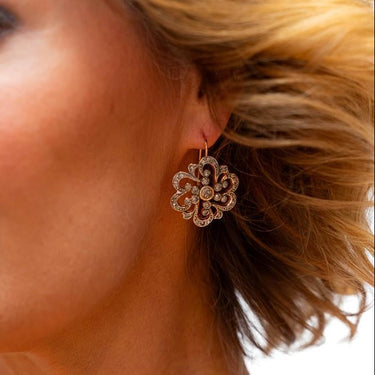 Close-up of a woman wearing a floral earring with a plain background