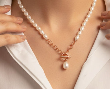 Pearl necklace with a rose gold clasp worn by a person