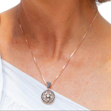 Close-up of a woman wearing a floral earring and necklace with a white top.