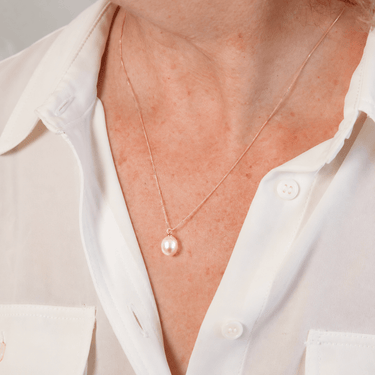 A pink pearl pendant with rose gold setting, attached to a box link chain necklace.